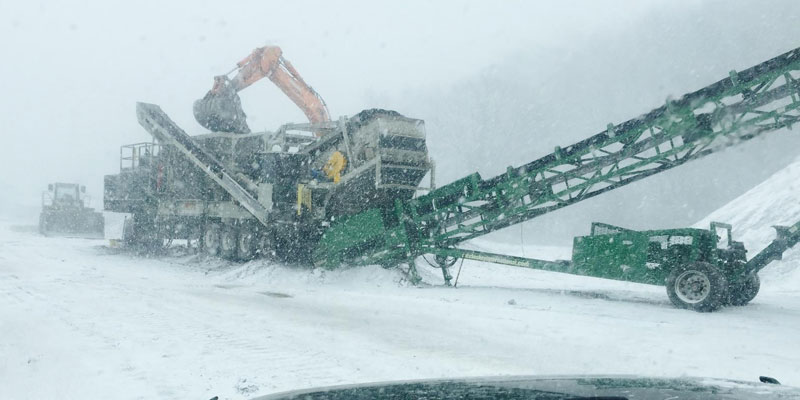 crushing construction equipment in a snow storm